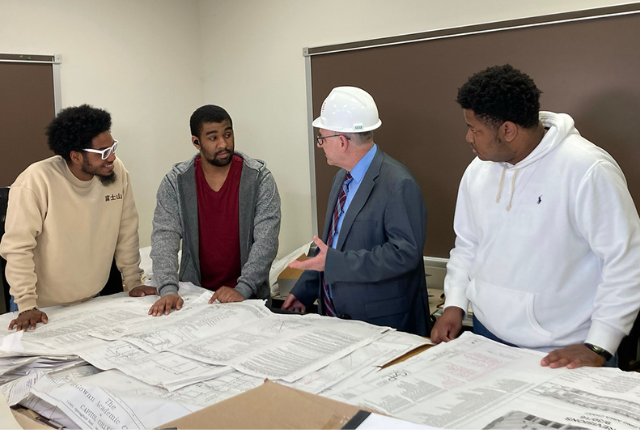 president sims going over construction blueprints with students 